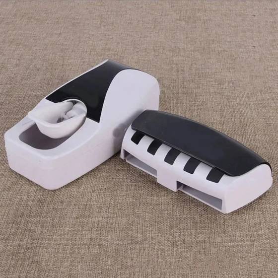 White and black toothpaste dispenser on a beige fabric background