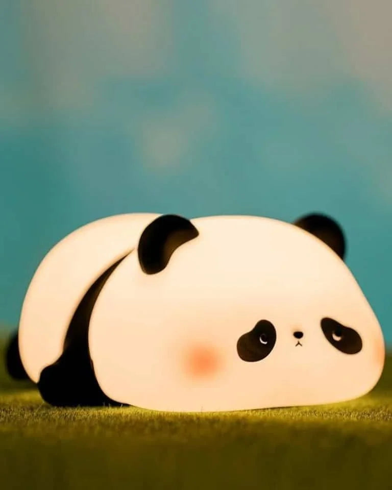 Cute panda-shaped night light on a green surface with a blue gradient background