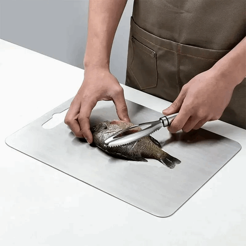 Person cleaning a fish on a cutting board with a knife