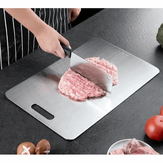Person cutting ground meat on a metal cutting board with a knife.